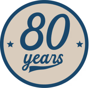 80th anniversary emblem: round beige badge with dark blue border and stars surrounding the text 80 years